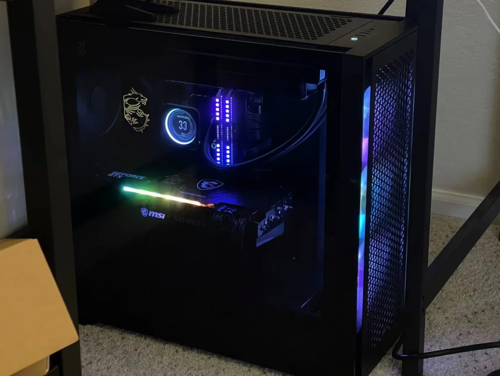 A dark tower photographed at night, its memory and graphics card lighting the inside of the case in blue and green